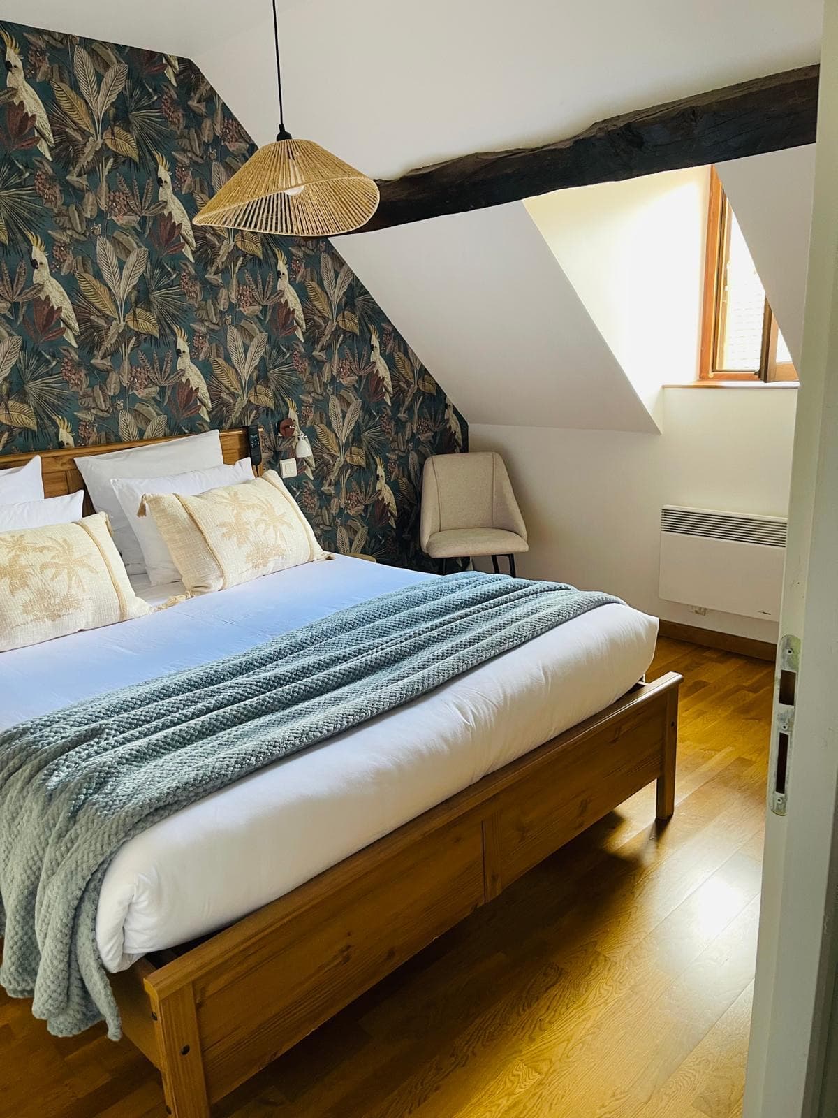 Schlafzimmer 1: Tapete mit Blattmotiv, Doppelbett und Hängeleuchte aus Seil unter den Balken