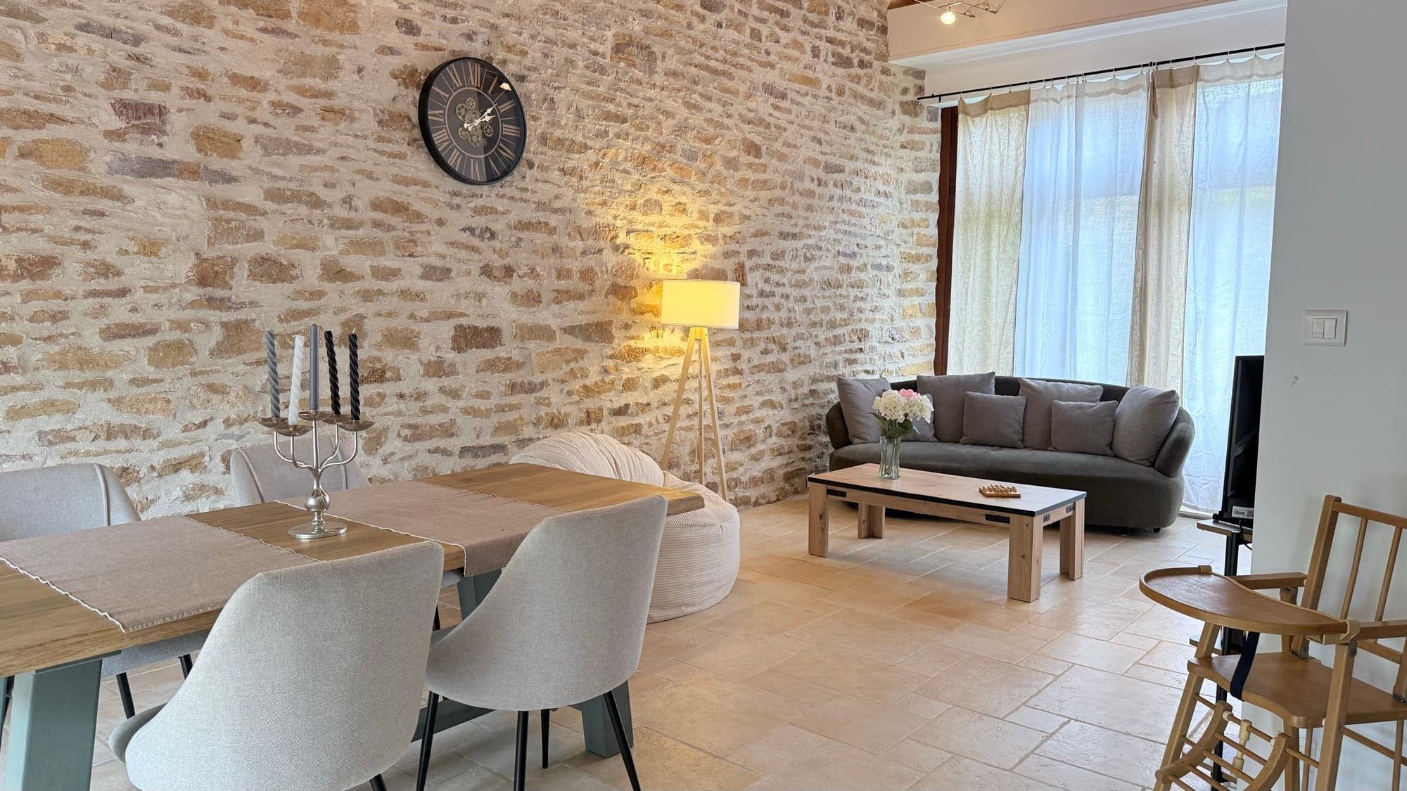 Pièce de vie au grand mur en pierres : salle à manger et coin salon