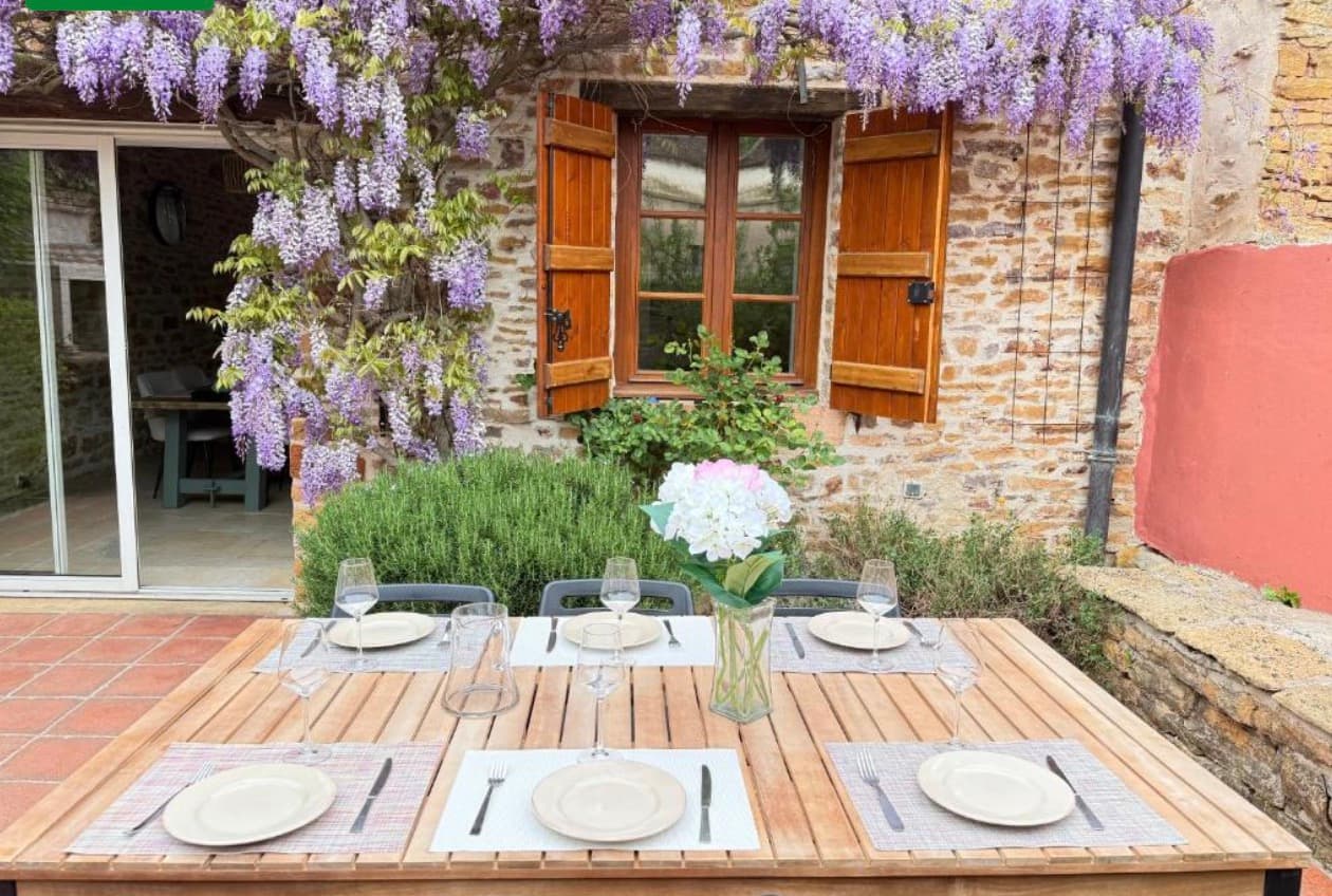 Terrasse fleurie avec table dressée sous la glycine en fleurs